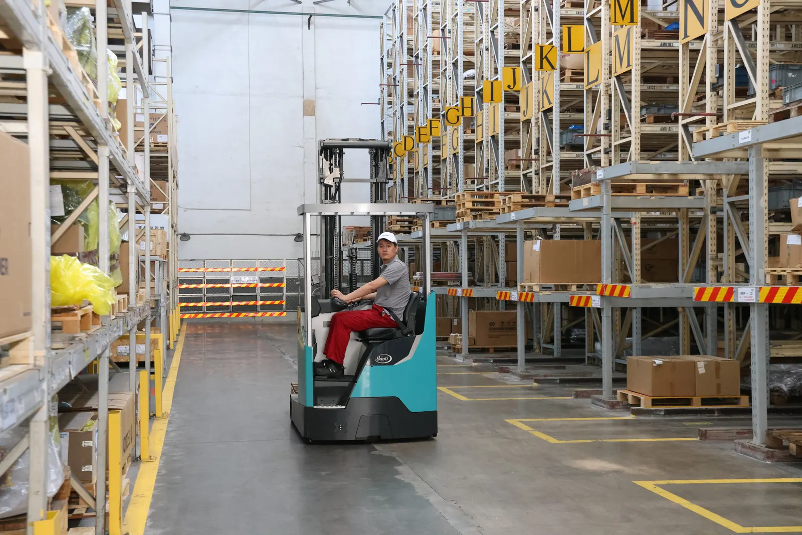Xe nâng reach truck Baoli KBR20L vận hành trong lối đi hẹp giữa hai dãy kệ